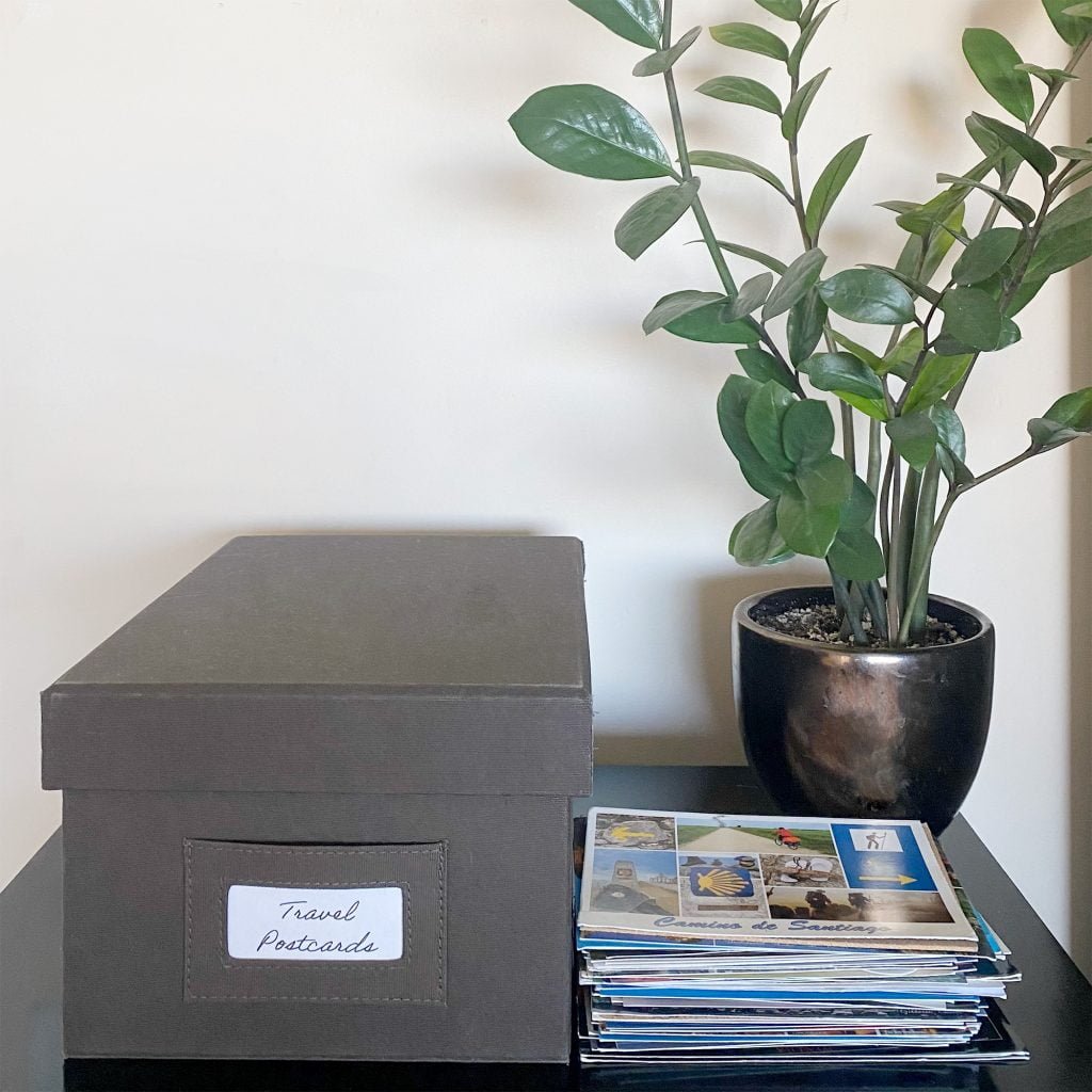 A stack of postcards and a postcard storage box